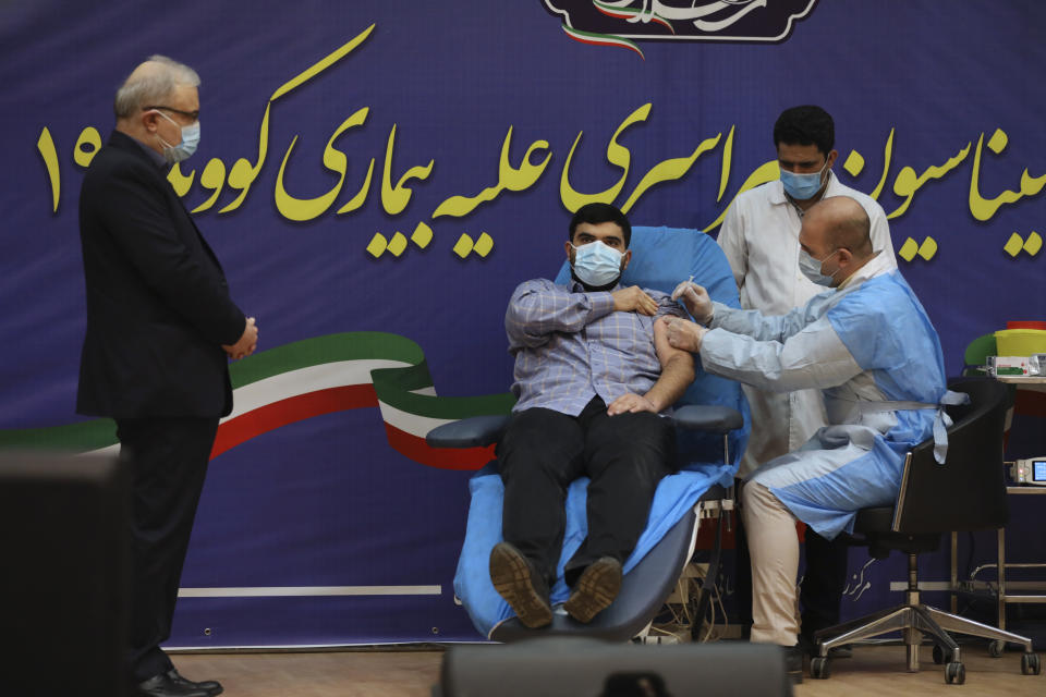 Parsa Namaki, center, son of Health Minister Saeed Namaki, left, is injected with the Russian Sputnik V coronavirus vaccine in a ceremony at Imam Khomeini hospital in Tehran, Iran, Tuesday, Feb. 9, 2021. Iran on Tuesday launched a coronavirus inoculation campaign among healthcare professionals with recently delivered Russian Sputnik V vaccines as the country struggles to stem the worst outbreak of the pandemic in the Middle East with its death toll nearing 59,000. (AP Photo/Vahid Salemi)