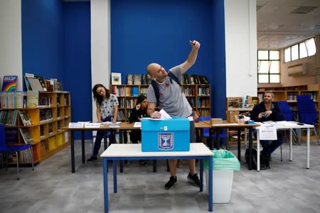 An man takes a selfie with his mobile phone as he casts his ballot in Israel's parliamentary election, at a polling station in Tel Aviv, Israel