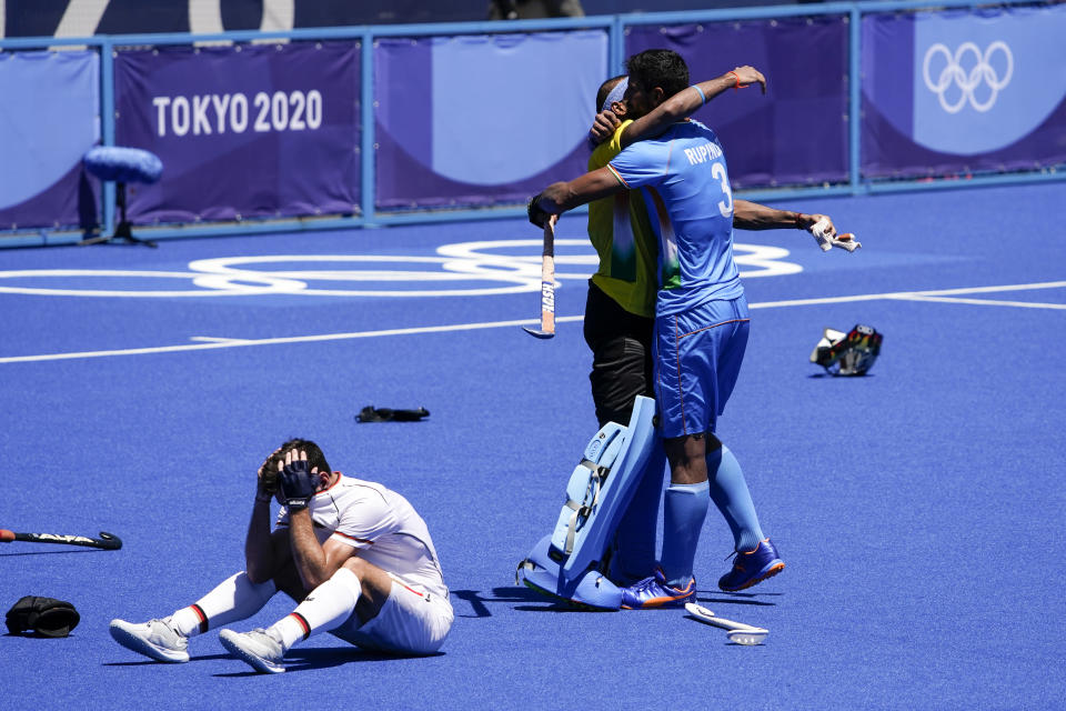 India's Rupinder Pal Singh (3) hugs goalkeeper Sreejesh Parattu Raveendran as Germany's Lukas Windfeder (4) reacts after India won their men's field hockey bronze medal match 5-4 at the 2020 Summer Olympics, Thursday, Aug. 5, 2021, in Tokyo, Japan. (AP Photo/John Locher)