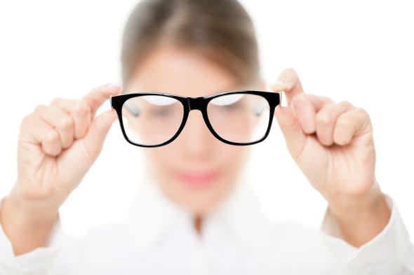 Glasses - optician showing eyewear. Closeup of glasses, with glasses and frame in focus. Woman optometrist on white background.