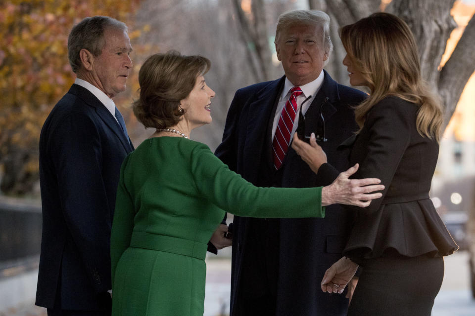 President Donald Trump, second from right, and first lady Melania Trump, right, are greeted by former President George Bush and former first lady Laura Bush outside the Blair House across the street from the White House in Washington, Tuesday, Dec. 4, 2018. (AP Photo/Andrew Harnik)