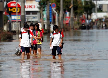 School girls make their way in a flooded area in Mabi town in Kurashiki, Okayama Prefecture, Japan, July 8, 2018. REUTERS/Issei Kato