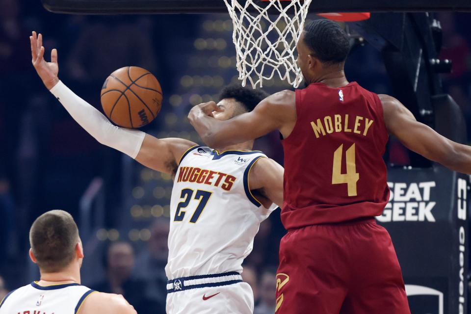 Cleveland Cavaliers forward Evan Mobley (4) defends a shot against Denver Nuggets guard Jamal Murray (27) during the first half of an NBA basketball game, Thursday, Feb. 23, 2023, in Cleveland. (AP Photo/Ron Schwane)