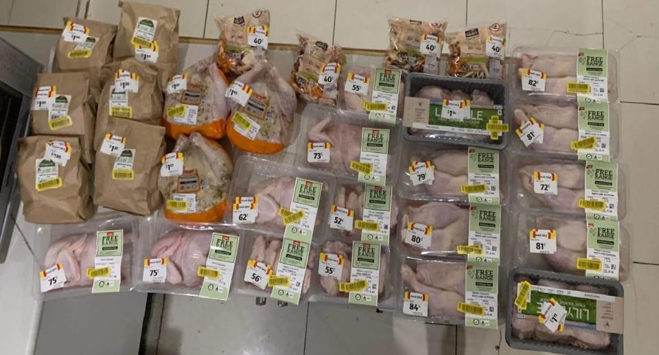 Table full of Coles meat products all with yellow discount stickers, plus potatoes and salad at discounted prices