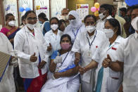 Hospital staff gathers around a health worker, sitting, after she received a COVID-19 vaccine at a government Hospital in Hyderabad, India, Saturday, Jan. 16, 2021. India started inoculating health workers Saturday in what is likely the world's largest COVID-19 vaccination campaign, joining the ranks of wealthier nations where the effort is already well underway. (AP Photo/Mahesh Kumar A.)