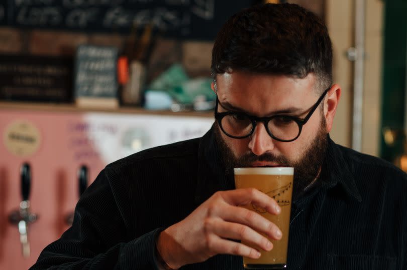 Luke O'Brien sampling one of the beers at his bar in Holmfirth -Credit:O'Briens