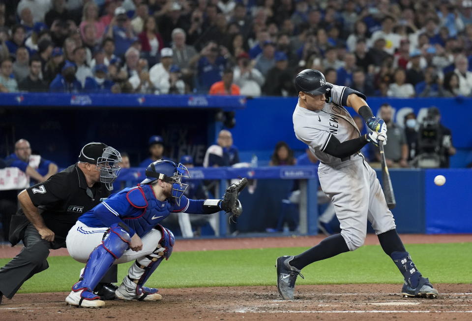 New York Yankees' Aaron Judge hits a two-run home run, his 61st homer of the season, next to Toronto Blue Jays catcher Danny Jansen during the seventh inning of a baseball game Wednesday, Sept. 28, 2022, in Toronto. (Nathan Denette/The Canadian Press via AP)