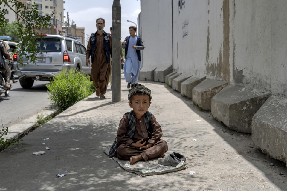 A child begs on a side walk in Kabul, Afghanistan, Sunday, May 22, 2022. Some 1.1 million Afghan children under the age of five will face malnutrition by the end of the year. , as hospitals wards are already packed with sick children . (AP Photo/Ebrahim Noroozi)