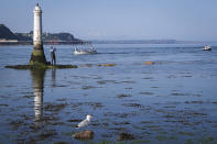 A man fishes next to the beacon in the Teign estuary in Shaldon, Devon, England, Monday July 19, 2021. (AP Photo/Tony Hicks)