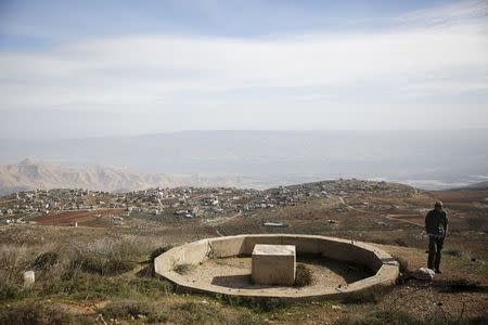 The West Bank village of Duma is seen in the background as Jewish settler Refael Morris walks in a field near Yishuv Hadaat, an unauthorized Jewish settler outpost January 5, 2016. REUTERS/Ronen Zvulun