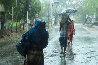 Residents walk along a street to a shelter ahead of the expected landfall of cyclone Amphan in Digha. (Photo by Dibyangshu SARKAR / AFP)