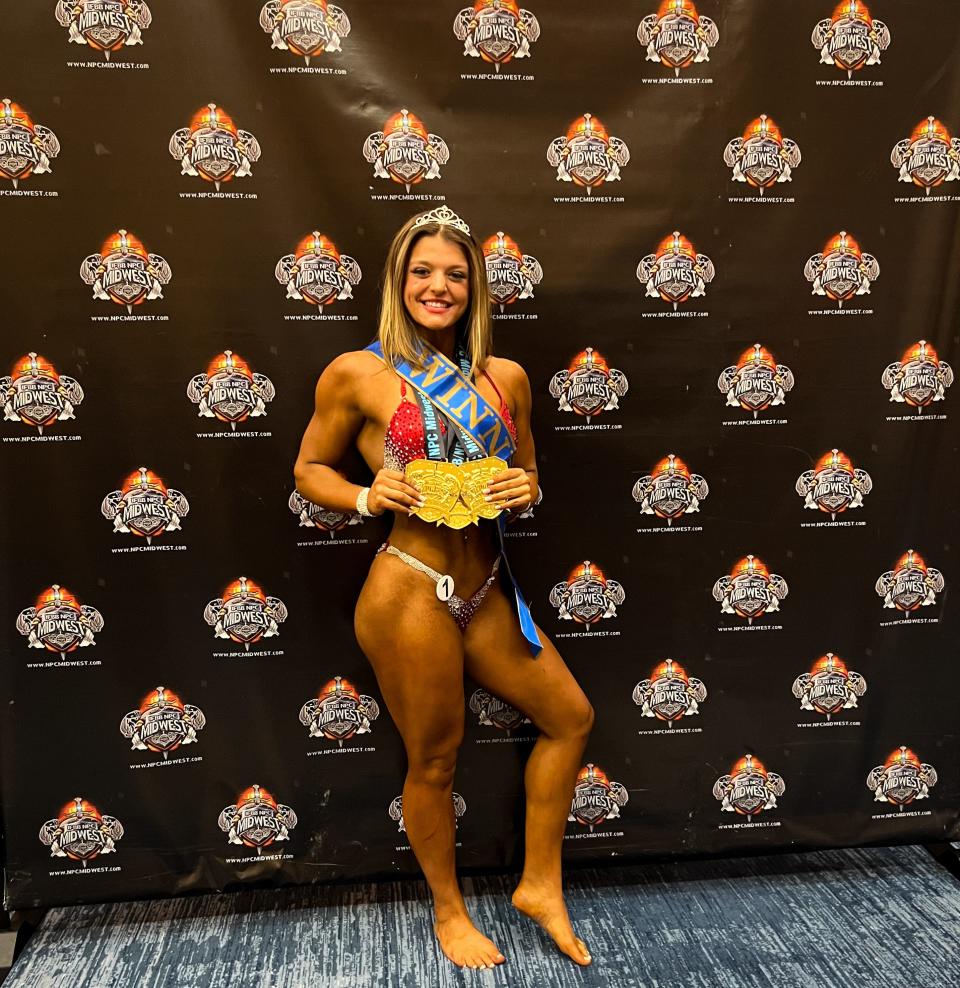Ashley Cadwell, a 2022 Webster Area High school graduate, holds up some hardware after winning her division in a bodybuilding competition.