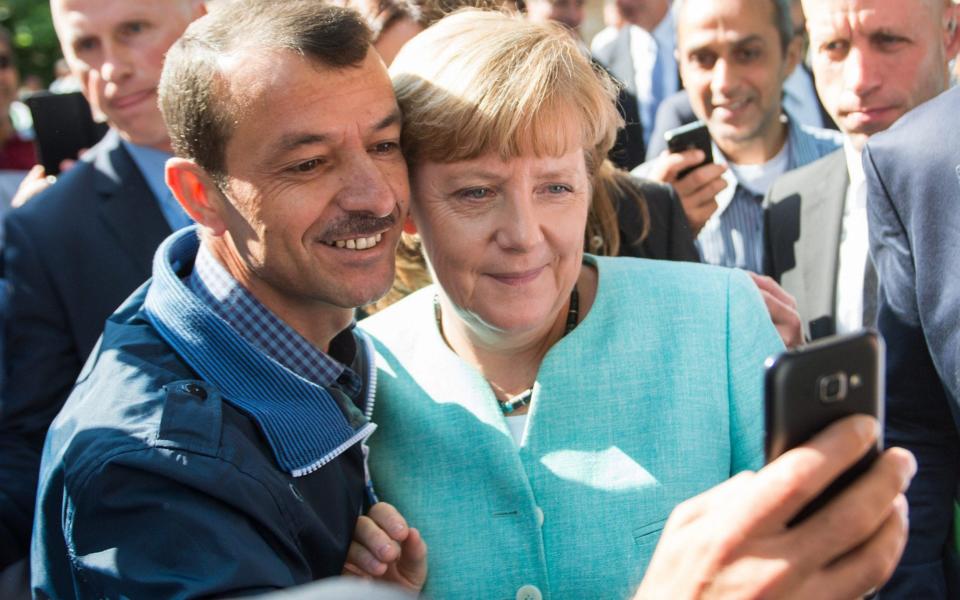 epa04923489 German Chancellor Angela Merkel (R) has a selfie taken with a refugee during a visit to a refugee reception centre in Berlin, Germany, 10 September 2015. Germany can deal with the arrival of hundreds of thousands of refugees without cutting social welfare benefits or raise taxes, Vice Chancellor Sigmar Gabriel said on 10 September, during a debate in parliament on next year's budget. Germany expects 800,000 asylum seekers this year, four times more than last year and more than any other country in the European Union, which is split on how to deal with the biggest refugee crisis since World War II. EPA/BERND VON JUTRCZENKA -  BERND VON JUTRCZENKA/DPA
