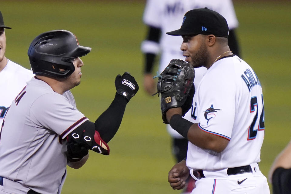 Arizona Diamondbacks' Asdrubal Cabrera, left talks with Miami Marlins first baseman Jesus Aguilar (24) after hitting a double during the first inning of a baseball game, Tuesday, May 4, 2021, in Miami. (AP Photo/Lynne Sladky)