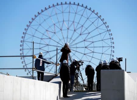Media members report as a Ferris wheel is a background at the construction site of the Kasai Canoe Slalom Centre for Tokyo 2020 Olympic games in Tokyo, Japan February 12, 2019. REUTERS/Issei Kato
