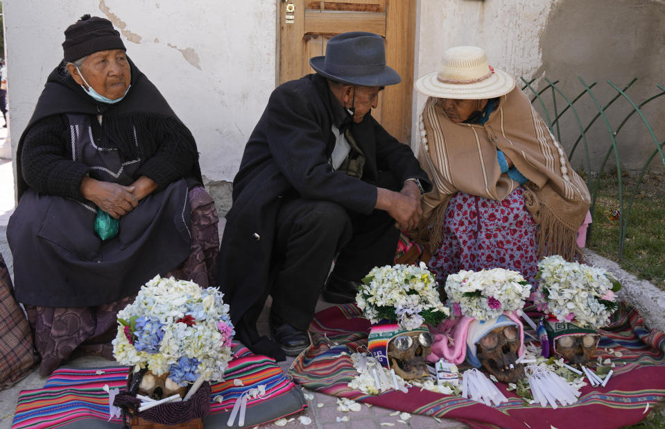 Las personas se sientan con sus cráneos humanos decorados para ser bendecidos por un sacerdote durante la fiesta anual de las ñatitas, una tradición que marca el final de la festividad católica de Todos los Santos, en el Cementerio General de La Paz, Bolivia, el martes 8 de noviembre de 2022. (AP Foto/Juan Karita)