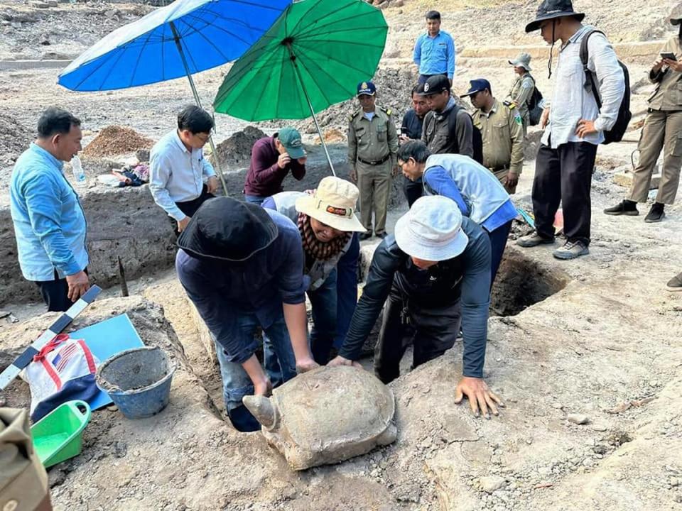 Archaeologists move the turtle statue found under a dried-up pond.