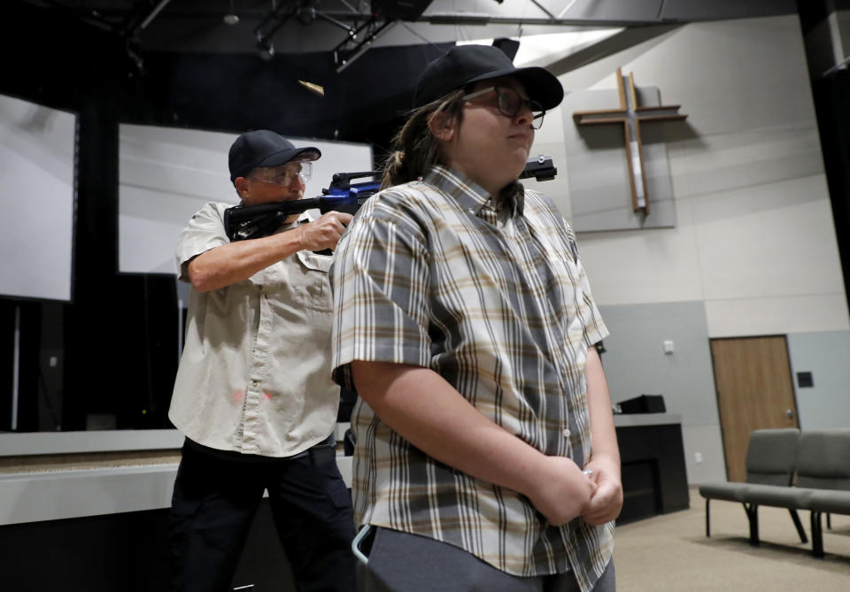 In this July 21, 2019 photo, Brett Faulkner, left, fires blanks out of an assault rifle as he and Julia Gant, right, participate in a hostage-taking scenario during a security training session at Fellowship of the Parks campus in Haslet, Texas. An industry has sprung up following mass shootings at houses of worship around the country to train civilians to protect their churches with the techniques and equipment of law enforcement. (AP Photo/Tony Gutierrez)