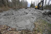 Thick, oozing mud is cleared from Washington Highway 530 by workers using heavy equipment, Tuesday, March 25, 2014, on the western edge of the massive mudslide that struck the area Saturday, killing at least 14 people and leaving dozens missing, near Arlington, Wash. (AP Photo/Ted S. Warren, Pool)