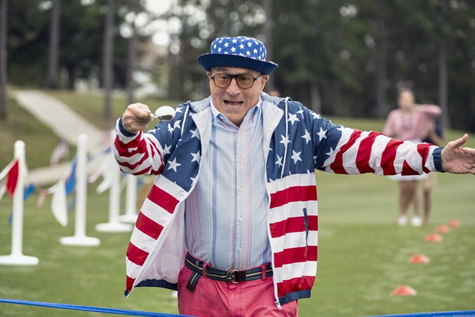 A man in an American Flag print coat walks with an egg on a spoon