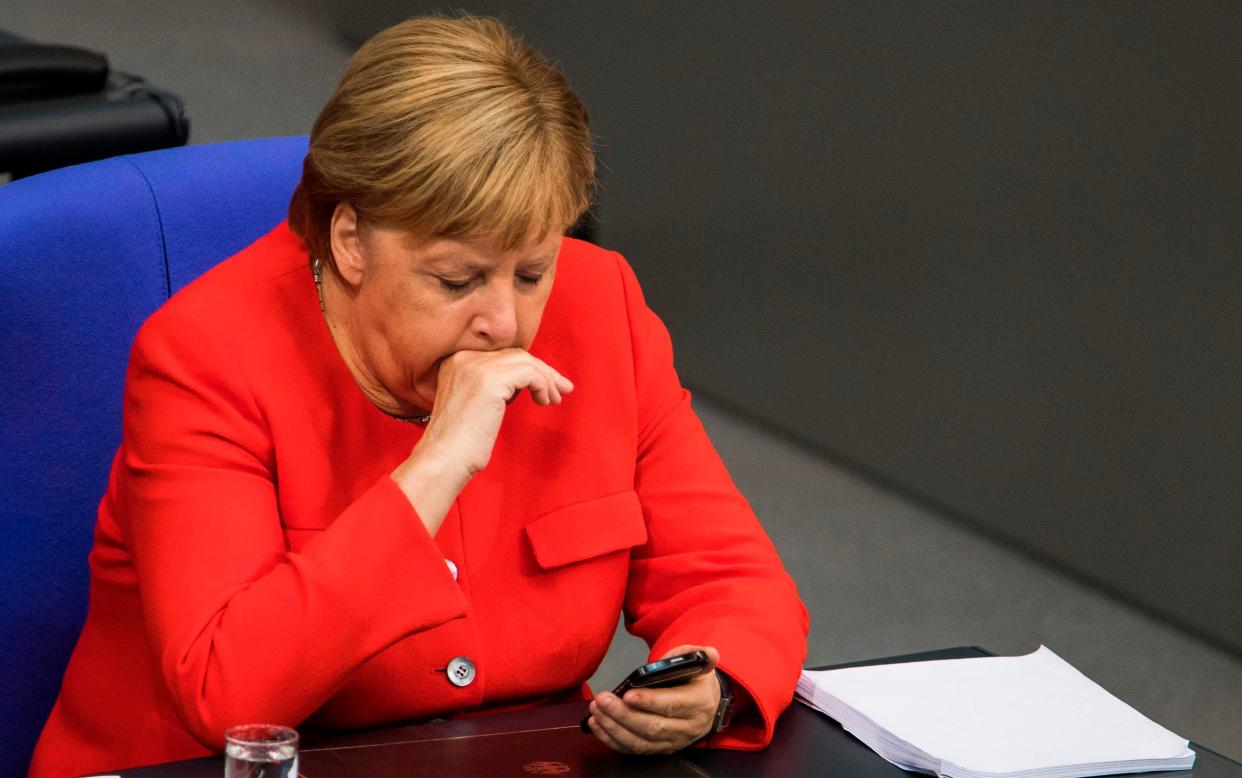 'When a phone rings, do you react as if a gun has gone off?' - Angela Merkel stares at her smartphone during a sitting of the Bundestag - AFP