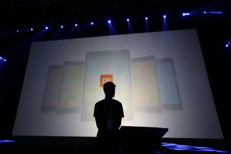 A security guard stands in front of a screen showing Xiaomi mobile phones ahead of the launching ceremony of Xiaomi Phone 4, in Beijing, July 22, 2014. REUTERS/Jason Lee/Files