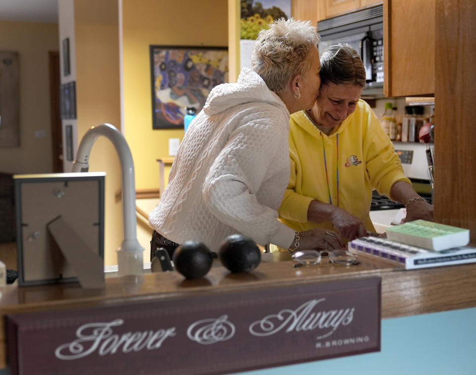 Deb Robertson kisses her wife Kate Koubek, as they prepare for a meal with family and friends at their Lombard, Ill., home Saturday, March 23, 2024. Robertson didn’t cry when she learned two months ago that the cancerous tumors in her liver were spreading, portending a tormented death. But later, she cried after receiving a call that a bill moving through the Illinois Legislature to allow certain terminally ill patients to end their own lives with a doctor’s help had made progress. (AP Photo/Charles Rex Arbogast)