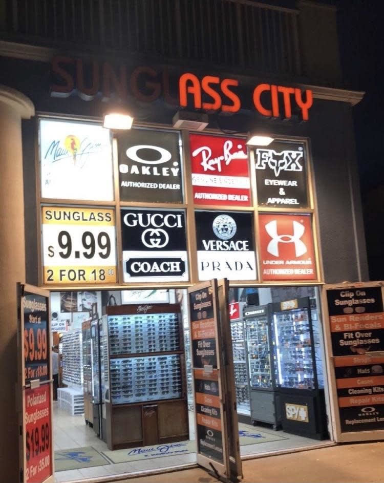 Signage for a sunglasses store with missing letters in 'SUNGLASSES CITY' making it read 'ASS CITY'