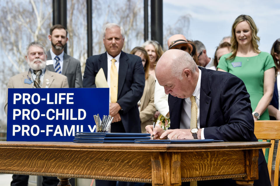 FILE - Gov. Greg Gianforte signs a suite of bills aimed at restricting access to abortion during a bill signing ceremony on the steps of the State Capitol, in Helena, Mont., on May 3, 2023. A judge on Thursday, May 18, 2023, granted Planned Parenthood of Montana's request to temporarily block enforcement of a law that bans the abortion method most commonly used after 15 weeks of pregnancy until he can hear arguments from both sides at a hearing on Tuesday, May 23. (Thom Bridge/Independent Record via AP, File)