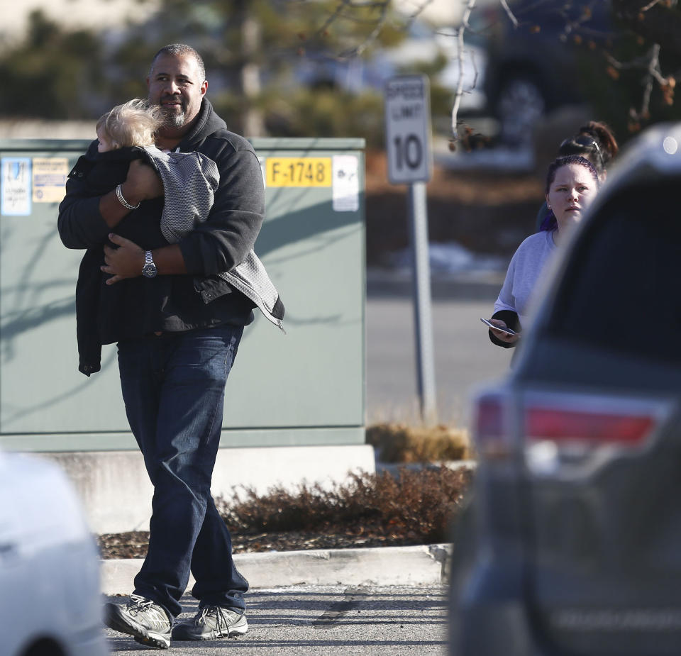 A man holding a child leaves the Fashion Place mall as police investigate a shooting at Fashion Place in Murray, Utah on Sunday, Jan. 13, 2019. (Silas Walker/The Deseret News via AP)