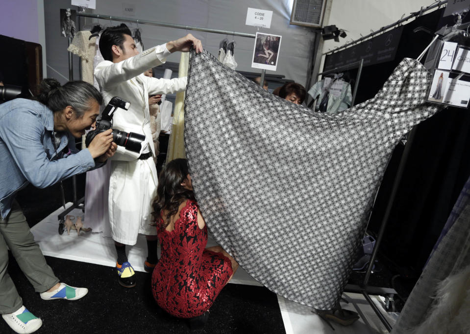 Workers steam dresses backstage before the Tadashi Shoji Spring 2014 collection is modeled during Fashion Week in New York, Thursday, Sept. 5, 2013. (AP Photo/Richard Drew)