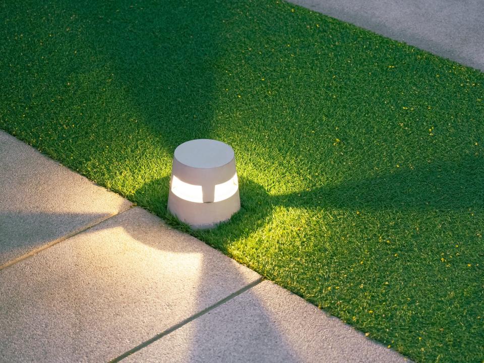 low cement light illuminating a walking path on an artificial turf lawn