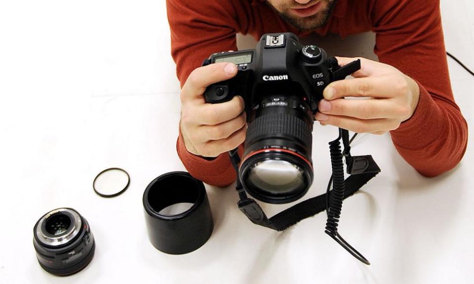 Photographer David Levene contemplates his camera whilst photographing a subject in a photographic studio. Jessops photography shop has posted a £50m loss. Commissioned