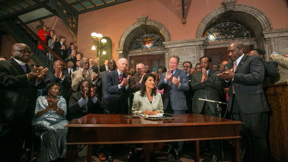 Haley, surrounded by three former governors, some family members of the slain nine, and many legislators, signing a bill to remove the Confederate flag from the Statehouse grounds on July 9, 2015. - Tim Dominick/The State/AP
