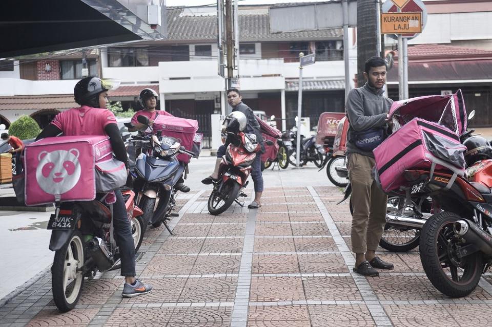 Food delivery riders have become extra careful about hygiene as they are out and about doing more food deliveries. — Picture by Miera Zulyana