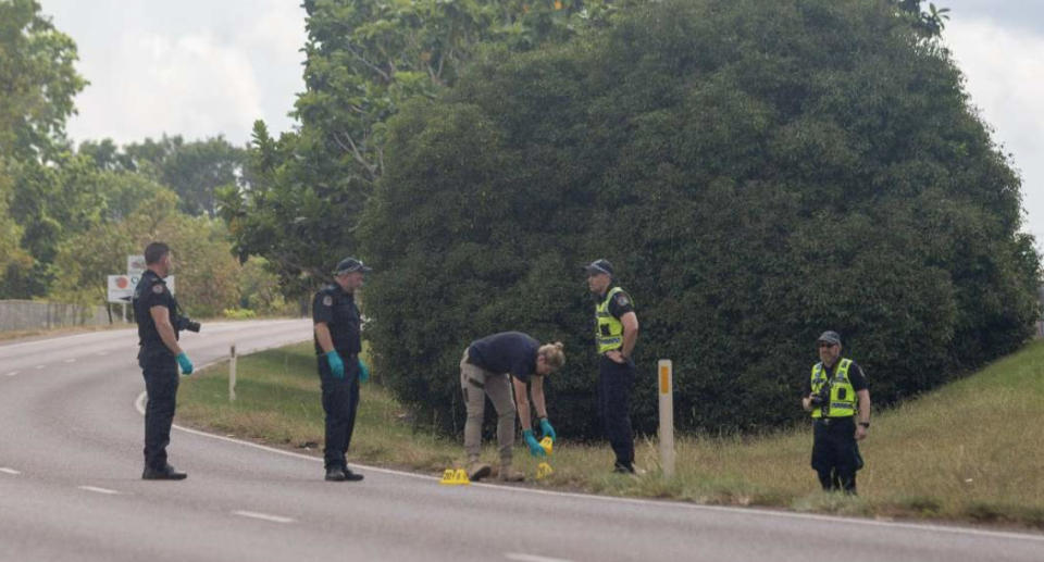 A group of police officers stand on a road