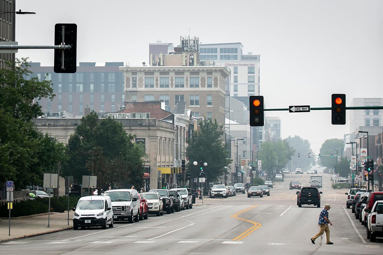 A person crosses Clinton Street as smoke from wildfires in Canada fills the air, Wednesday, June 28, 2023, in Iowa City, Iowa.