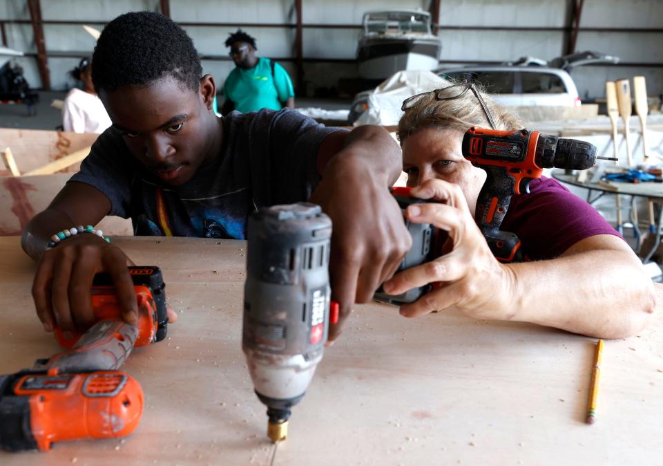 Donte Adams, 17, of Detroit, left, works at drilling holes for screws in the bottom of a 12-foot Bevin's Skiff as boat builder Deb Scott, 65, of Franklin, helps and guides him at Riverside Marina in Detroit on Aug. 10, 2022. Adams and other teenagers from metro Detroit participated in the weeklong Detroit River Skiff and Schooner program through the University of Michigan's Detroit River Story Lab.