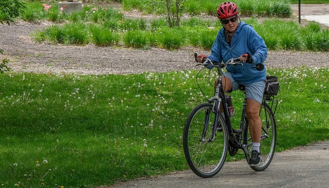 A woman rides her bike on the Lansing River Trail Sunday, May 14, 2023.