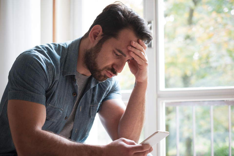 Worried man watching smartphone and waiting message