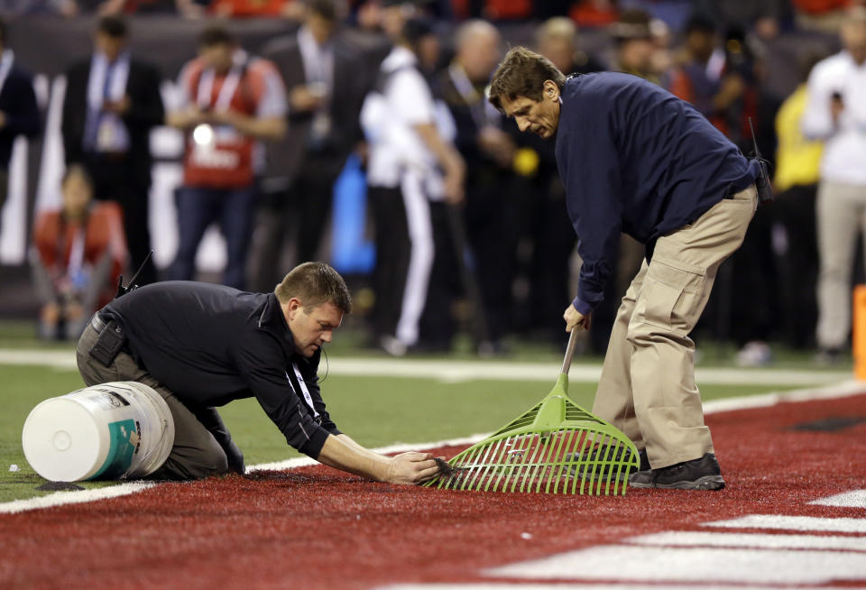 FILE - Workers fix a problem with the artificial turf during the second half of the Big Ten championship NCAA college football game between Ohio State and Wisconsin, Dec. 2, 2017, in Indianapolis. (AP Photo/Michael Conroy, File)