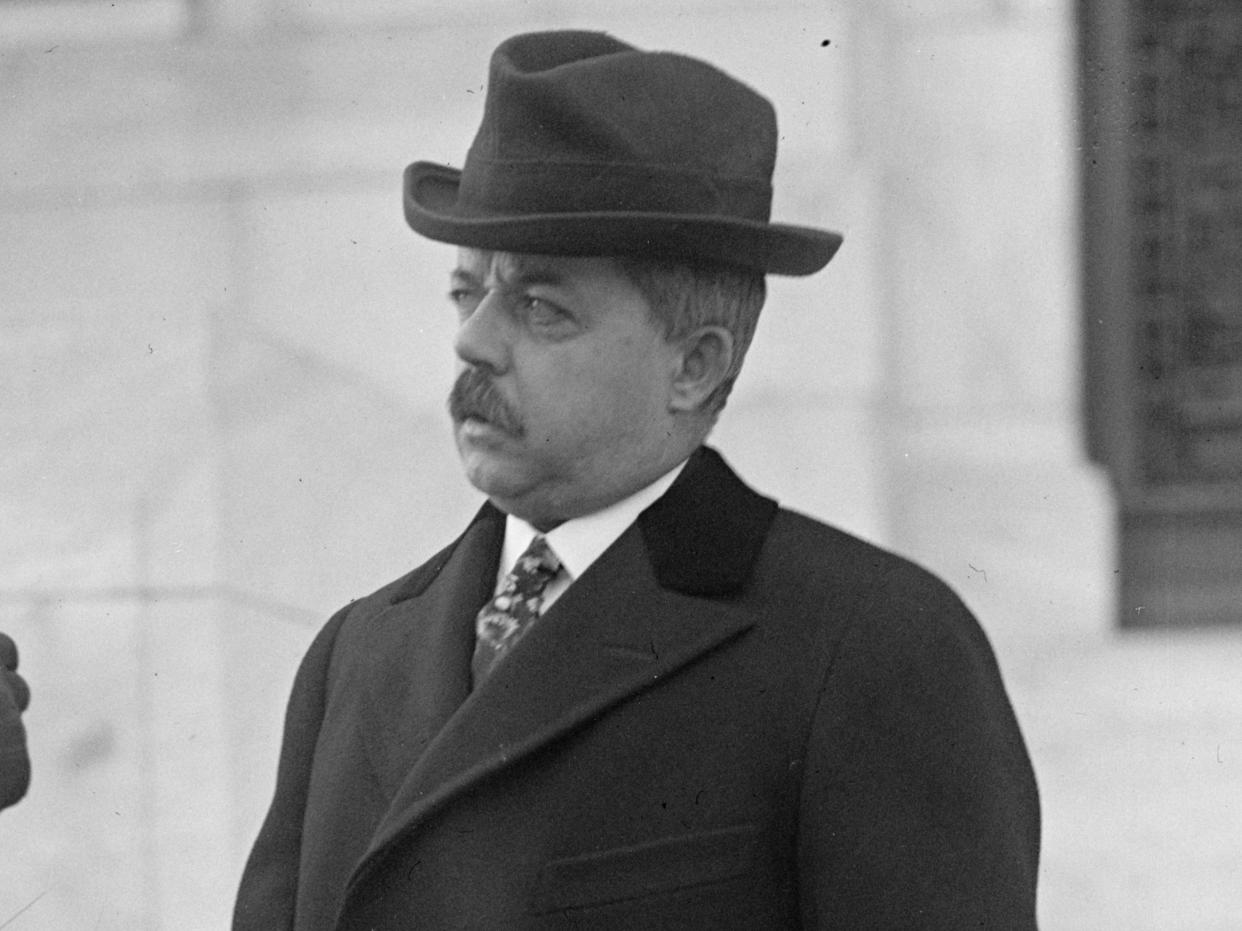 Joseph Holton Defrees standing in front of a building while wearing a hat and a black overcoat.