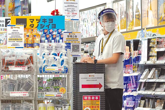 圖為台北街頭冷冷清清，日系連鎖藥妝店的店員戴上口罩及面罩，在入口處等候客人上門。（黃世麒攝）