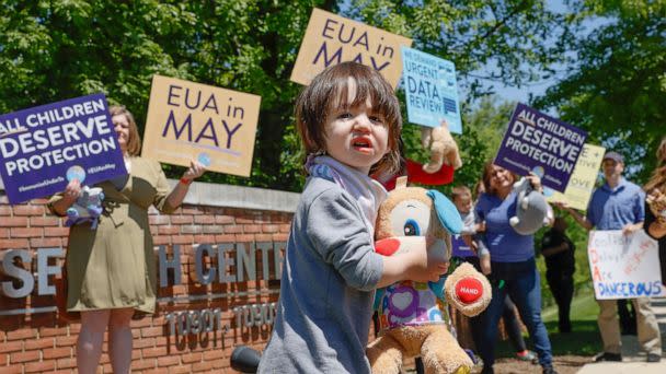 PHOTO: A child walks in front of demonstrators holding up signs urging the Food and Drug Administration to authorize vaccines for children under 5 at the FDA on May 9, 2022 in Washington, D.C. (Jemal Countess/Getty Images for Protect Their Future, FILE)