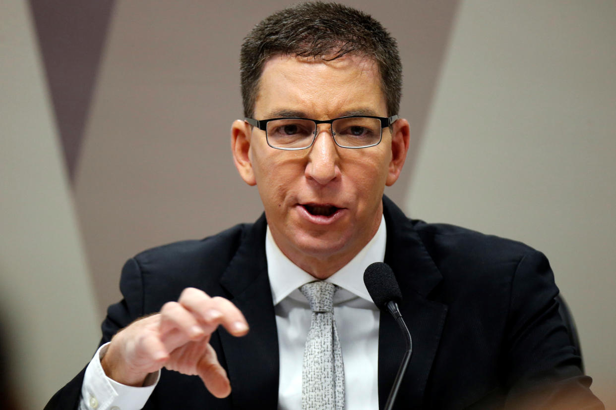 Glenn Greenwald speaks into a microphone at a meeting in Brazil.