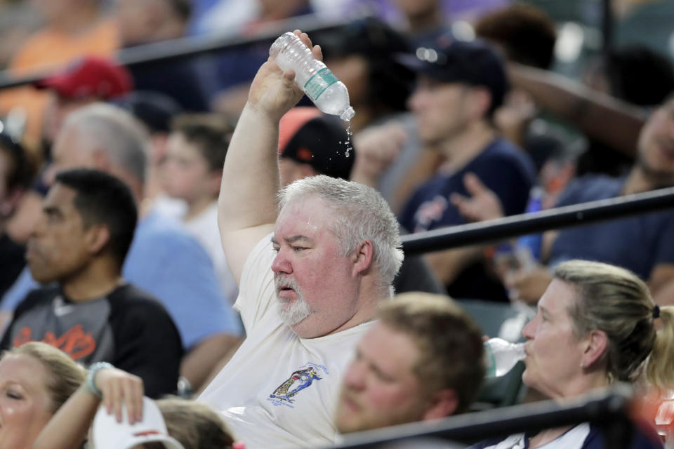 A spectator drops water on his head while watching the fourth inning of a baseball game between the Baltimore Orioles and the Boston Red Sox in hot weather, Saturday, July 20, 2019, in Baltimore. Temperatures reached the high 90s in Baltimore with the real feel over the triple digit mark. (AP Photo/Julio Cortez)