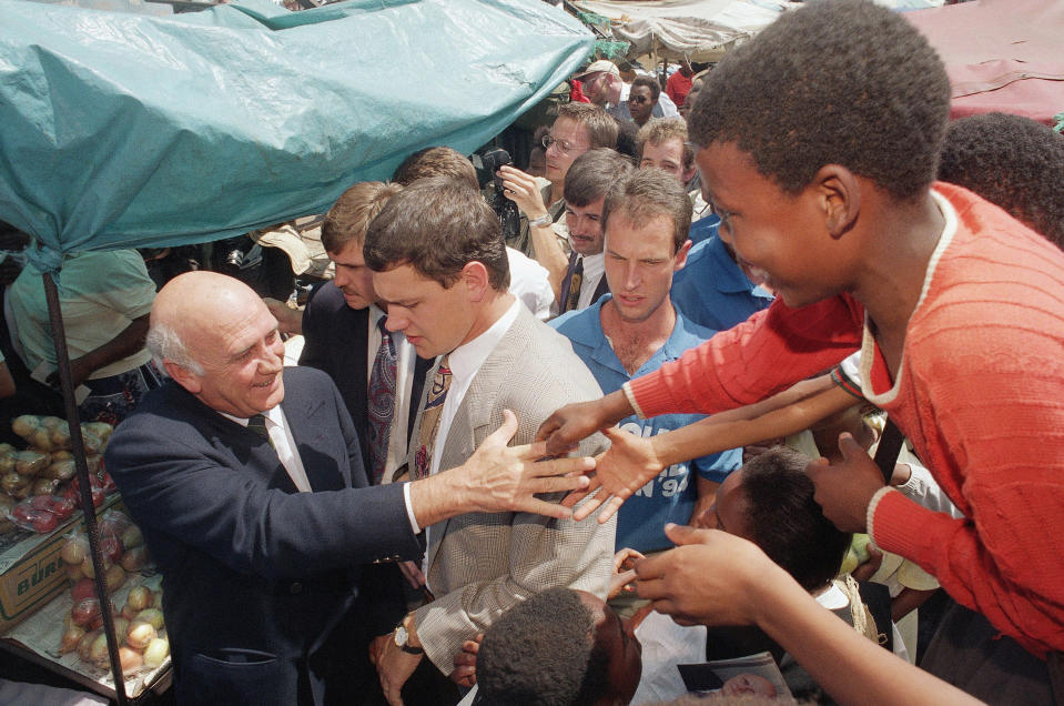 FILE - South African President F.W. de Klerk reaches out to greet young supporters while campaigning for votes ahead of the country's first multiracial elections, in Soweto, South Africa, March 17, 1994. South Africa is engrossed in debate over the legacy of apartheid's last president, de Klerk, who died at 85 and is to be buried Sunday, Nov 21, 2021. Some people want to remember de Klerk as the liberator of Nelson Mandela, but others say he was responsible for racist murders. (AP Photo/Peter Dejong, File)