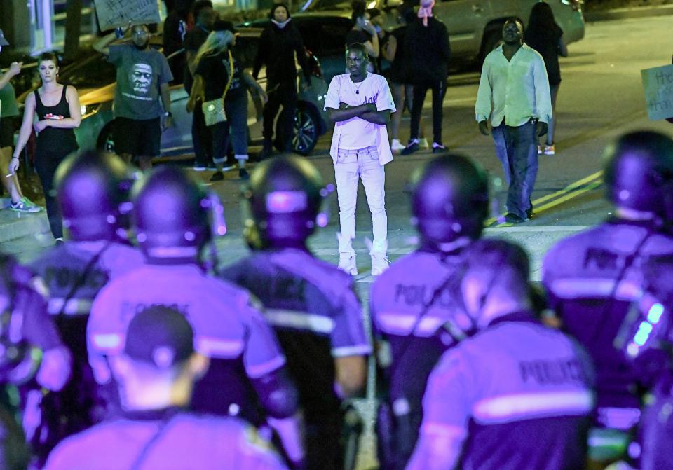 A man stands with his arms crossed before flash cans were set off in an attempt to send people home during a protest remembering George Floyd at Falls Park in Greenville, S.C. on  Sunday. "Go home, the protest is over," a voice said over a loudspeaker on top of a police car slowly moving toward the crowd.