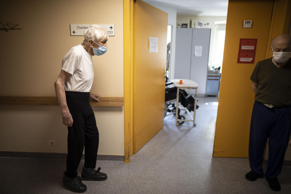 Richard Eberhardt, left, and Rene Dolers make a few steps along a corridor at a nursing home in Kaysesberg, France Thursday April 16, 2020. The elderly make up a disproportional share of coronavirus victims globally, and that is especially true in nursing homes, which have seen a horrific number of deaths around the world. (AP Photo/Jean-Francois Badias)
