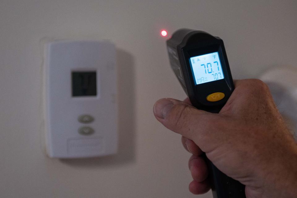 A worker with Florida Power & Light uses a laser thermometer to verify the accuracy of a residential thermostat during a Home Energy Audit performed in March in Delray Beach.